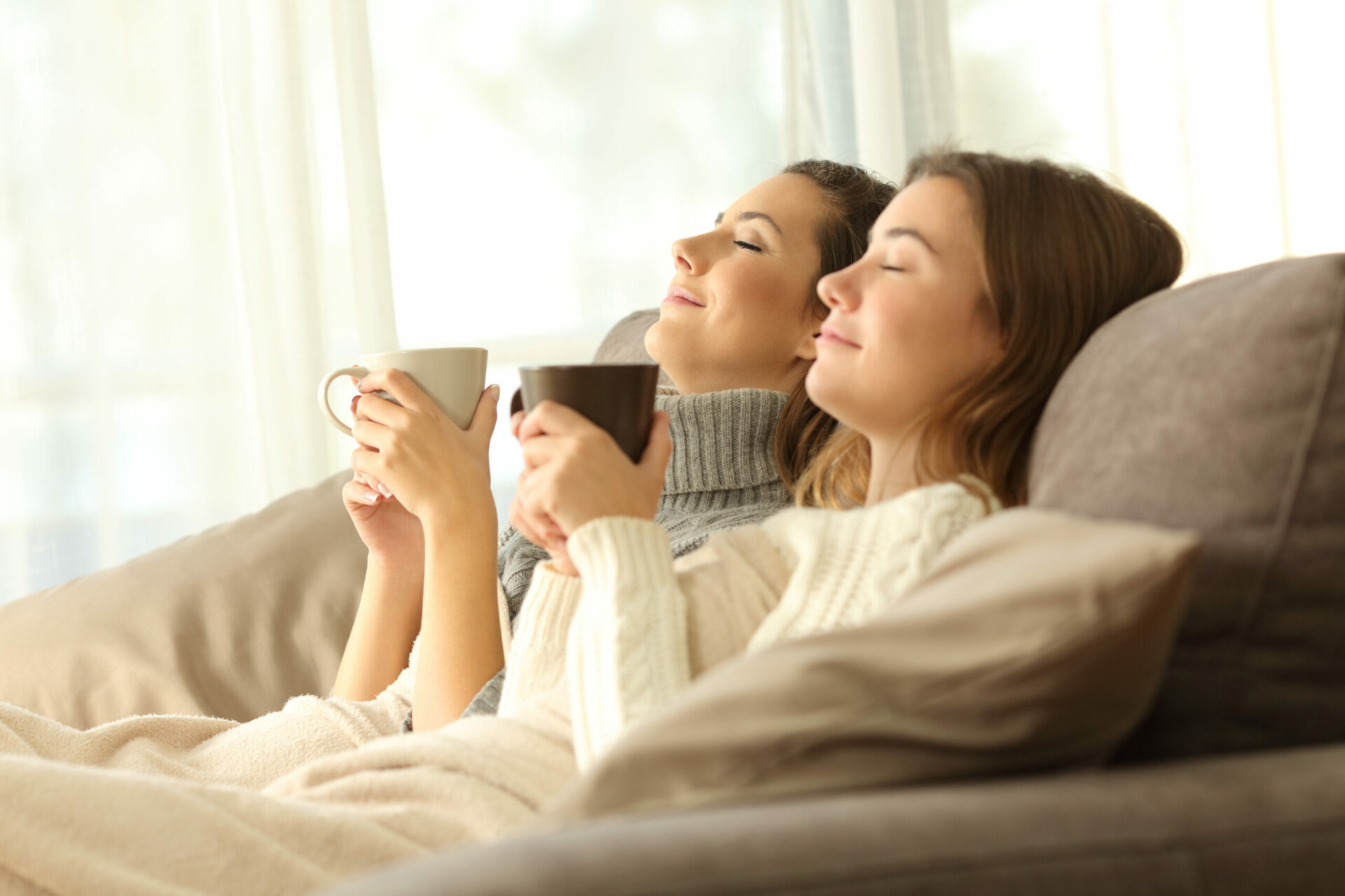 Zwei Frauen die entspannt auf dem Sofa Tee trinken