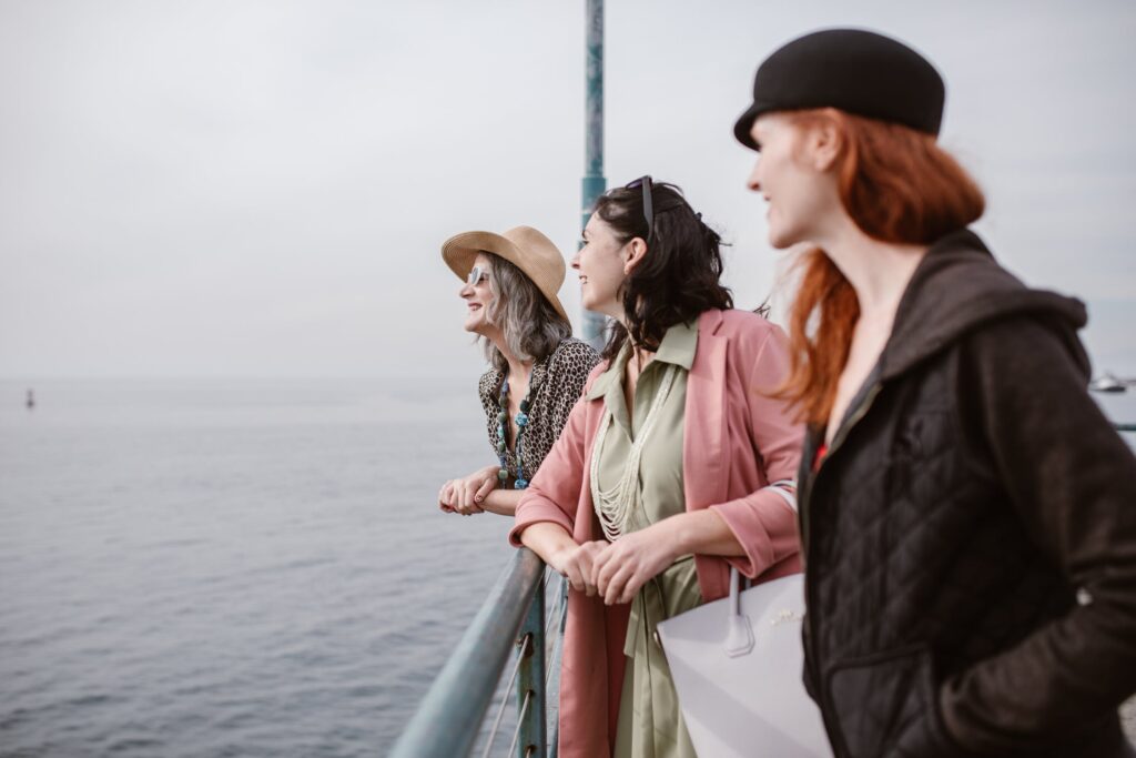 three women, who could be in the age of menopause, stand on the shore and look into the distance