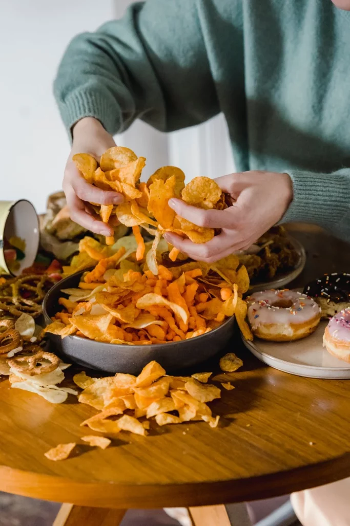 ein Tisch voller Chips, Donuts und weiterer ungesunder Lebensmittel verkörpert eine ungesunde Ernährung