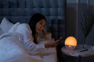 Frau liegt nachts im Bett und schaut auf ihr Smartphone