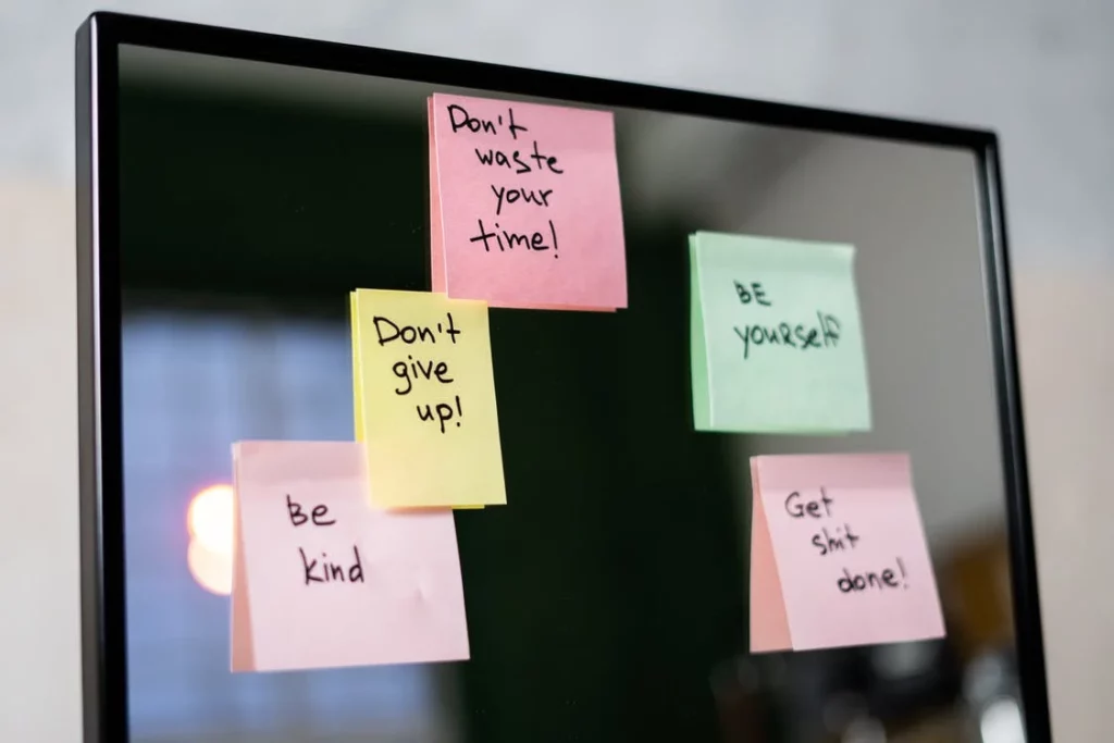 Notes with motivational sayings hang on screen