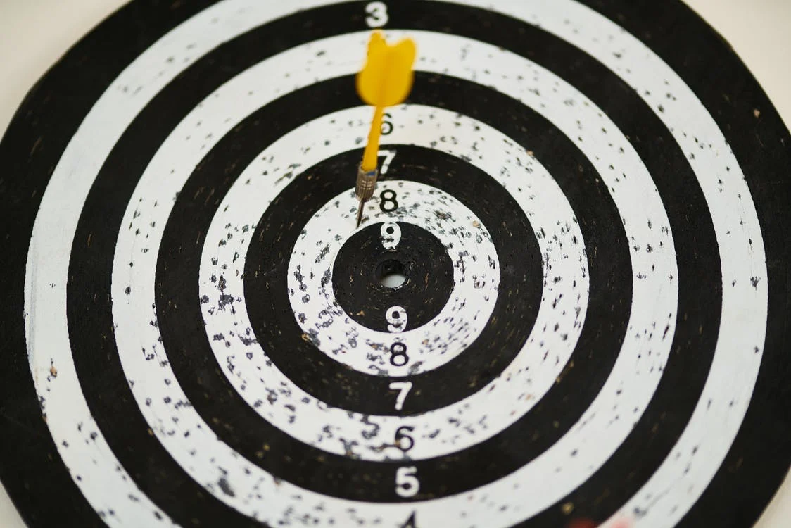Dartboard with yellow arrow almost in the middle
