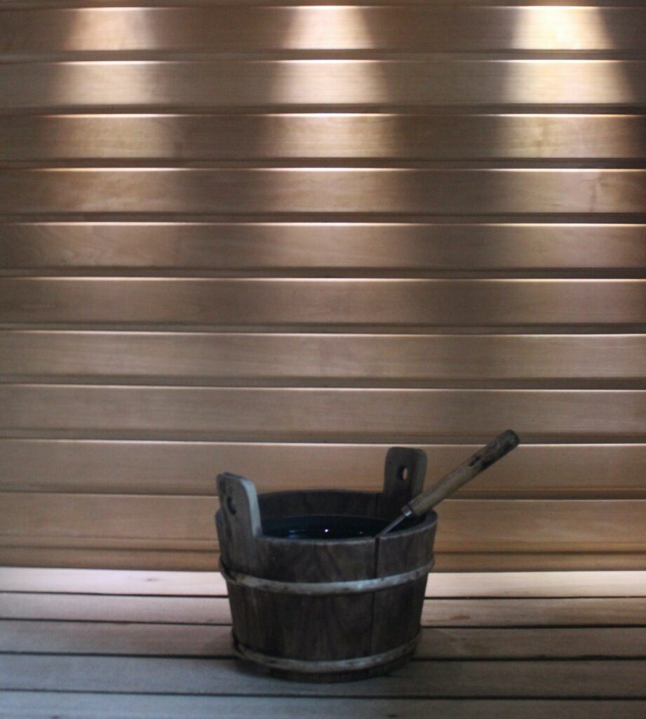 Aufgusskübel mit Schöpfkelle in der Sauna mit Scheinwerfern im Hintergrund