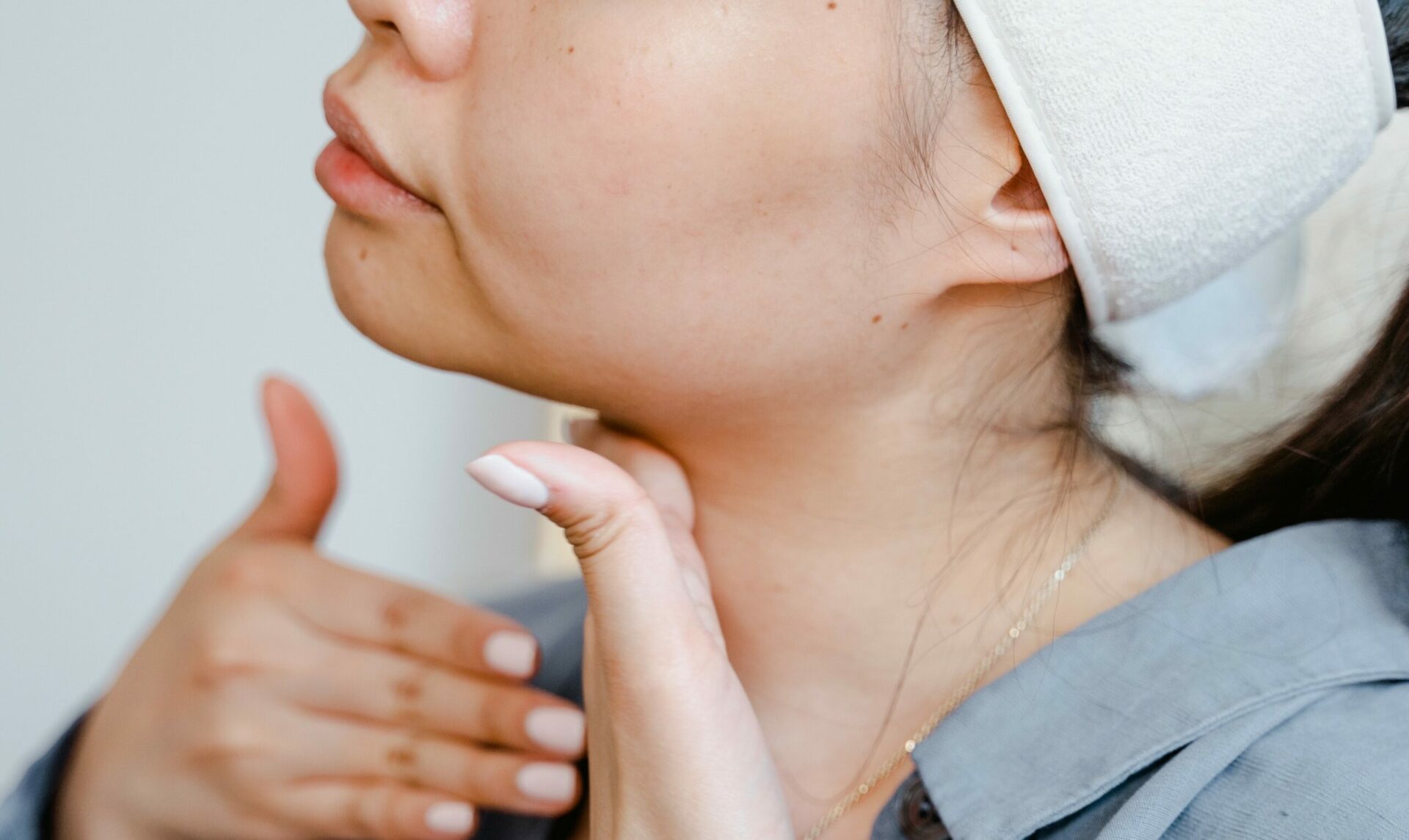 Young woman palpating her neck