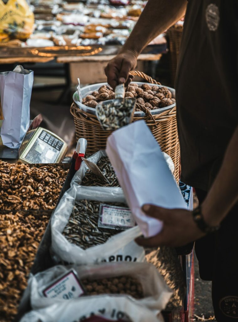 Nüsse auf einem Wochenmarkt, Person schüttet Nüsse in Beutel