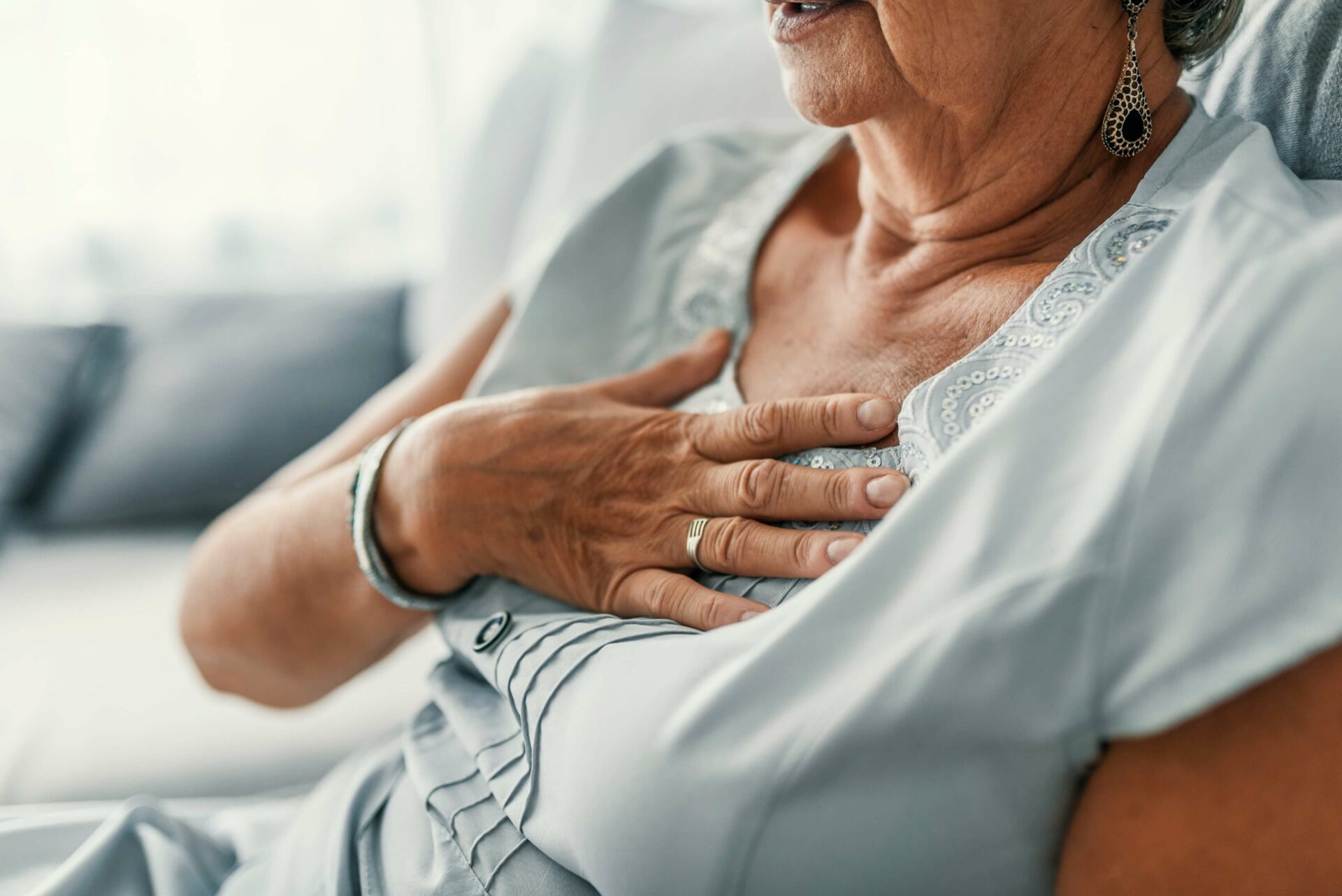 elderly woman grabs her chest because of heartburn