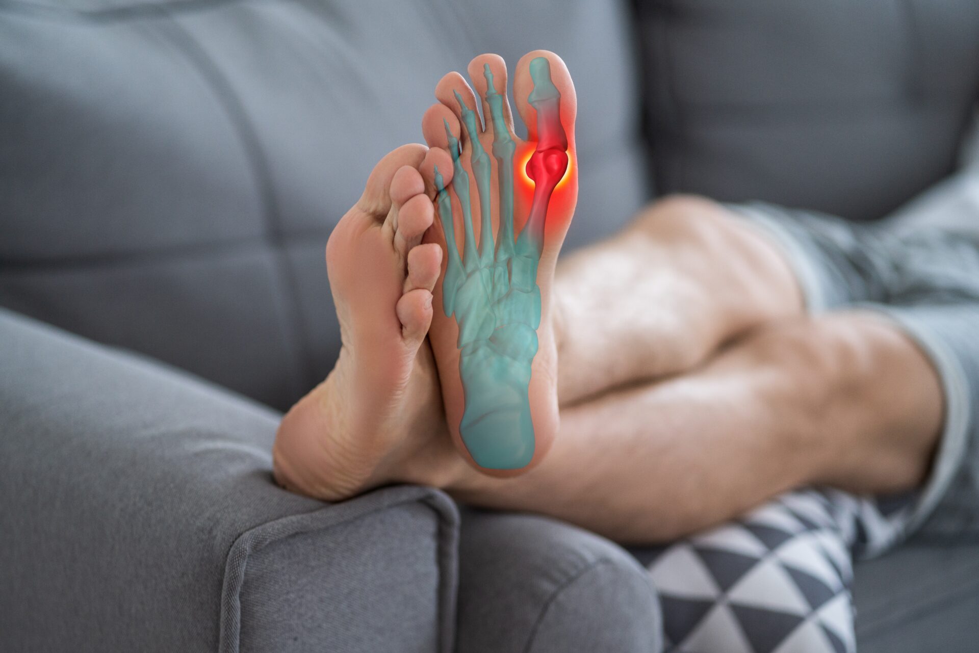 Person is sitting on a couch with their legs crossed. The tendons and joints of one foot are clearly visible. The big toe joint is colored red.