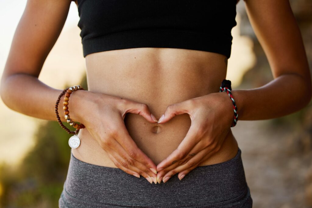 Woman holding her hands in a heart in front of her stomach