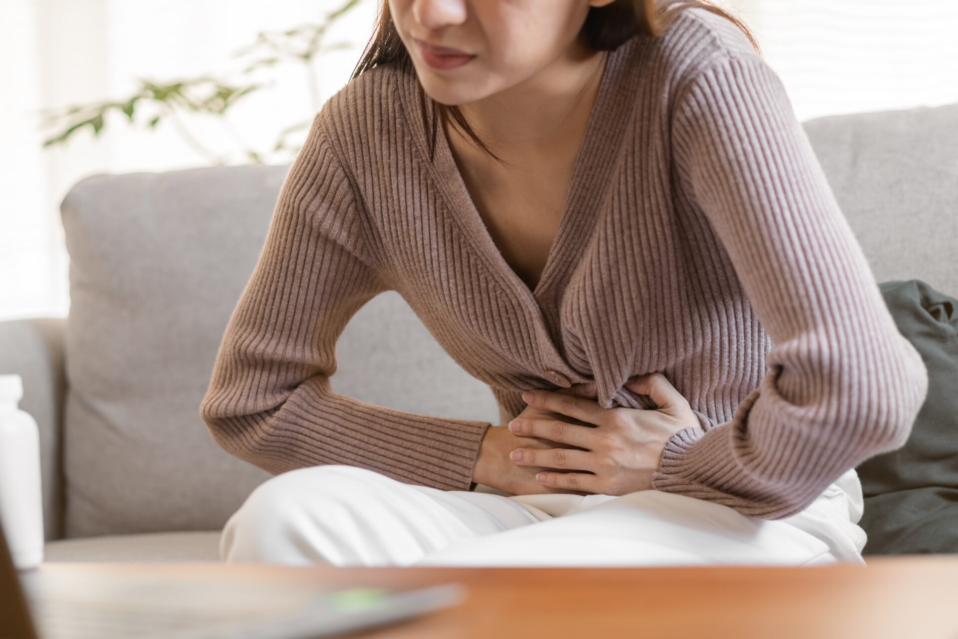 Frau haelt sich vor Schmerzen den Bauch (Gastritis)