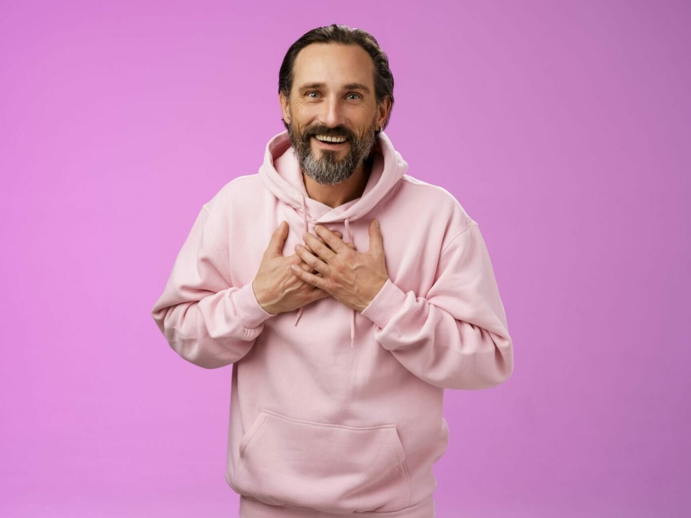 Man with pink sweater in front of pink wall grabs his chest and is relieved that his soda burning is gone by herbal help from Zimply Natural